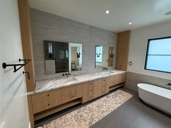 After: long wood double vanity with a stone top in a remodeled primary bath, Lake Sherwood