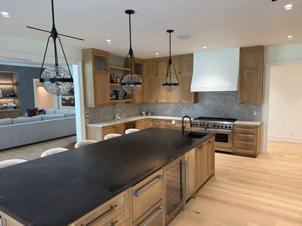 After: stained white oak kitchen with a long dark-topped island, glass-front uppers and a white range hood, Lake Sherwood