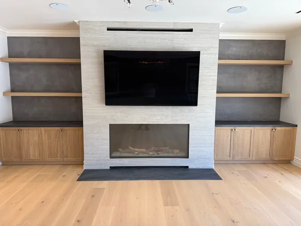 Media wall with a stone fireplace surround, floating shelves and light oak base cabinets in Lake Sherwood, Westlake Village