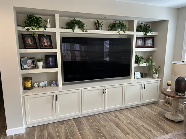 White built-in media wall with open shelves, display niches and base cabinets around a large TV, Camarillo