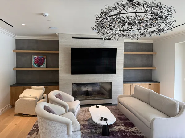 Family room media wall with a TV above the fireplace and floating shelves over base cabinets on both sides, Lake Sherwood