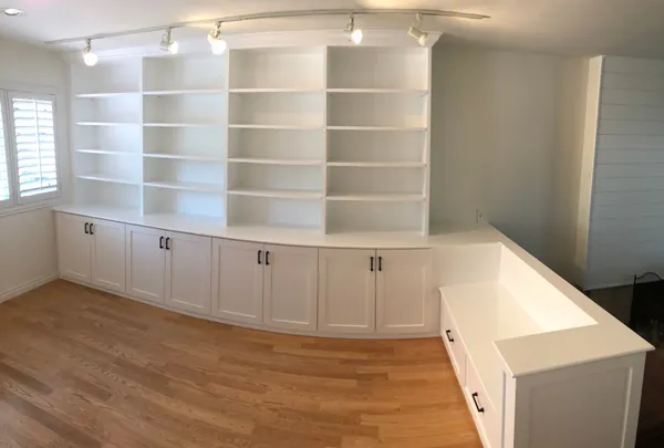 White wall-to-wall bookcases over base cabinets wrapping a room, Thousand Oaks