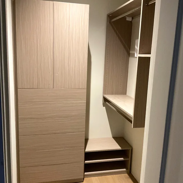 Walk-in closet with a textured oak-look wardrobe tower, drawers, hanging space and shoe shelves