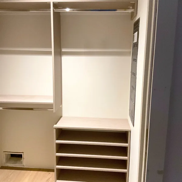Closet section with two hanging rods above open shoe cubbies in an oak-look finish