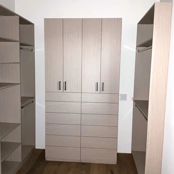 Straight-on view of a wardrobe tower with four doors over six drawers, flanked by open hanging and shelves
