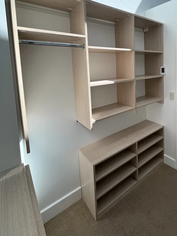 Light oak-look hanging and shelving unit with a low shoe cubby bench below a skylight, Solvang