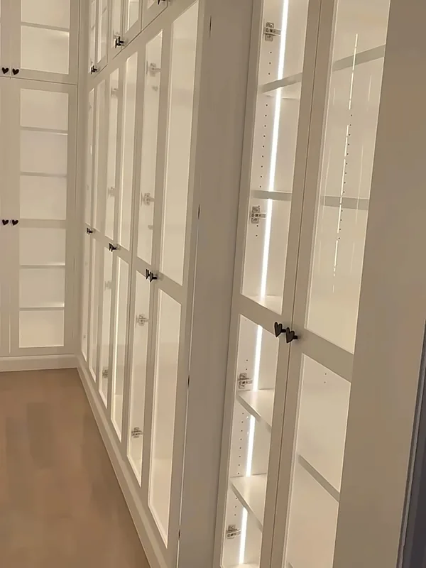 Long aisle of floor-to-ceiling white glass-front cabinets with LED-lit shelves