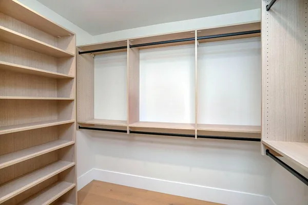 Walk-in closet with a light oak shelving tower, long hanging rods and an open shelf wall, Thousand Oaks