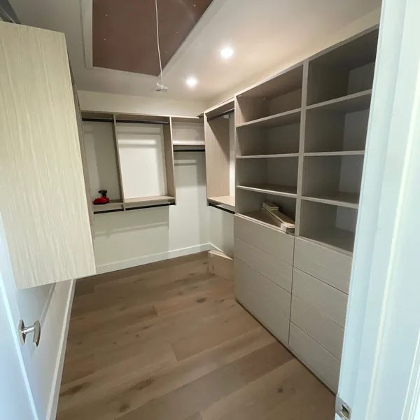 Walk-in closet with white shelving towers, a drawer bank and double hanging