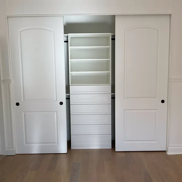 Reach-in closet with arched sliding doors around a white center organizer