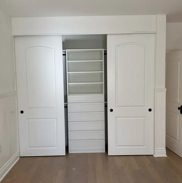 Reach-in closet with sliding doors open to white shelves and drawers