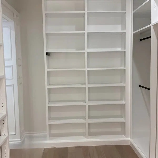 Walk-in closet with white shelving towers and LED shelf lighting