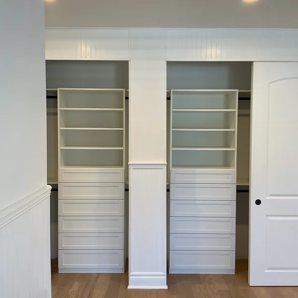 Walk-in closet with twin white shelf and drawer towers and beadboard