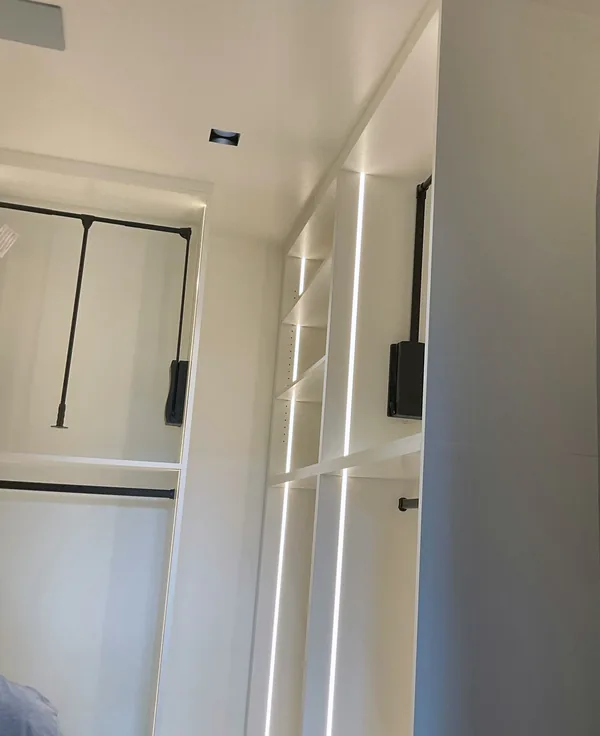 White closet shelving with LED lighting beside hanging space