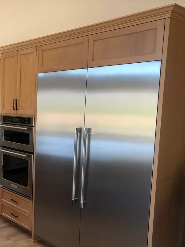 Light oak cabinetry framing a built-in refrigerator, with a double wall oven tower and crown molding, Santa Rosa Valley