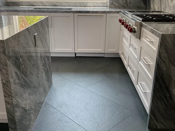 White shaker kitchen with stone waterfall ends and a pro-style range, Calabasas