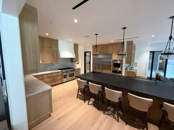 Oak shaker kitchen with a large black-topped island, white range hood and pendant lights, Thousand Oaks