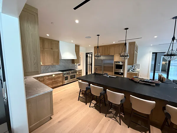 Open white oak kitchen with a long dark-topped island, pendant lights and bar seating in Lake Sherwood, Westlake Village