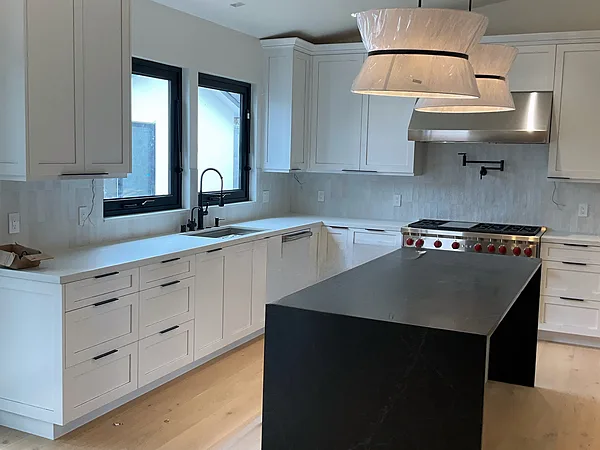 White shaker kitchen with a black waterfall island and woven pendants, Westlake Village