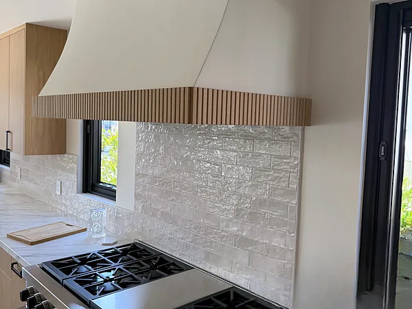 Plaster range hood with a wood-slat band over a professional range, Westlake Village