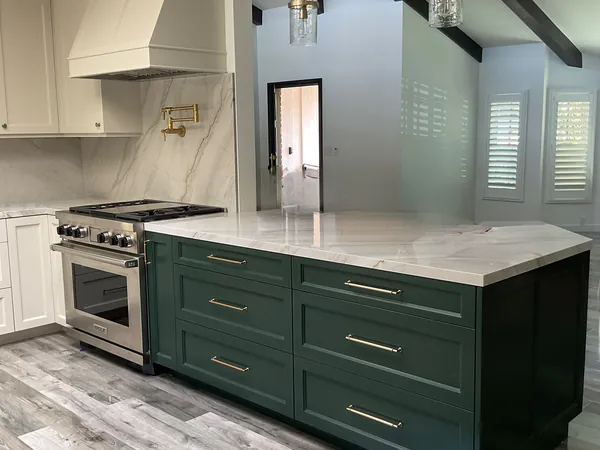Green shaker island with brass pulls and a marble-look top beside a white kitchen, Thousand Oaks