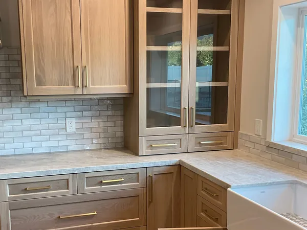 Light oak shaker cabinets with glass-front uppers, brass pulls and a farmhouse sink, Thousand Oaks