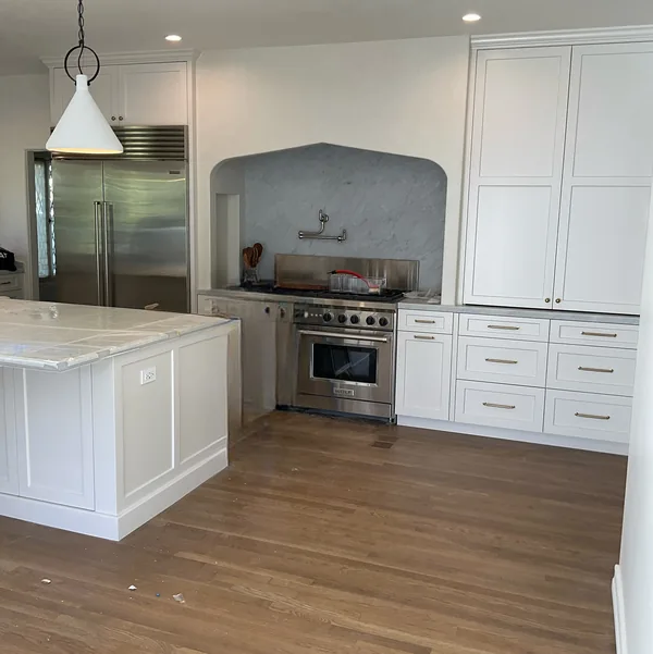 White shaker kitchen with an island and an arched range alcove