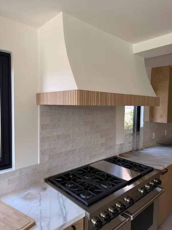 Plaster range hood with a wood-slat band over a professional range, Westlake Village