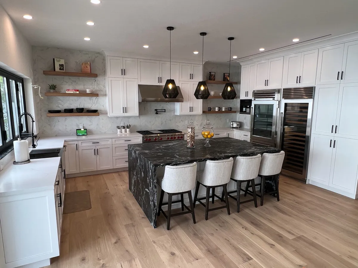 White kitchen with a large dark stone island, open shelves and pendant lights, Westlake Village