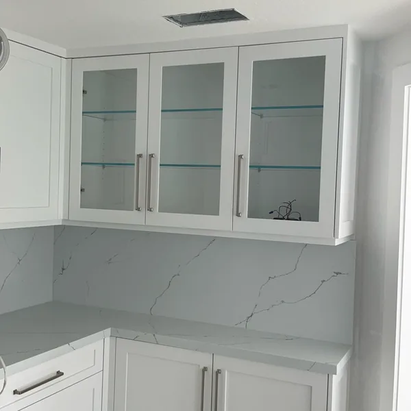 White shaker cabinets with glass-front uppers and glass shelves over a quartz backsplash, Simi Valley