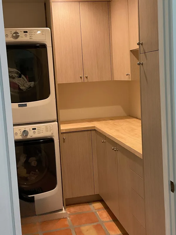 Laundry room with light wood cabinets, a stacked washer and dryer and a counter run, Thousand Oaks