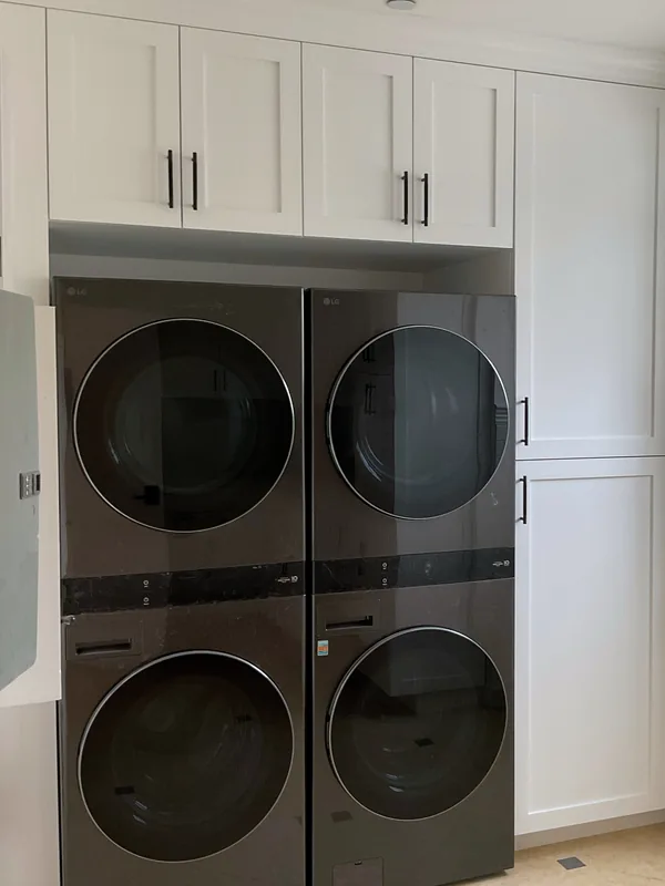 Stacked washer and dryer pair set into tall white shaker cabinets, Hidden Hills