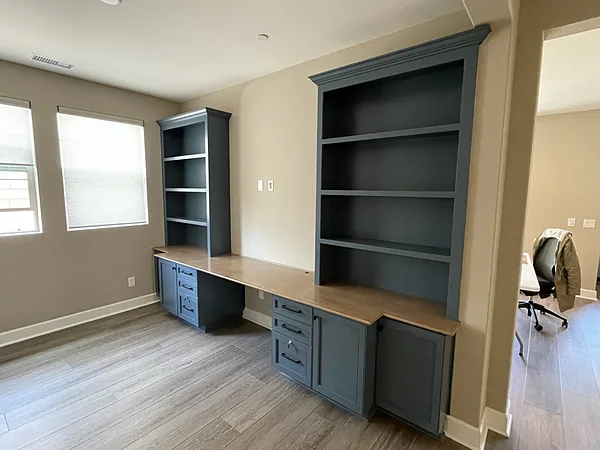 Blue-gray built-in double desk with drawer stacks and open bookcase towers in a Camarillo home office