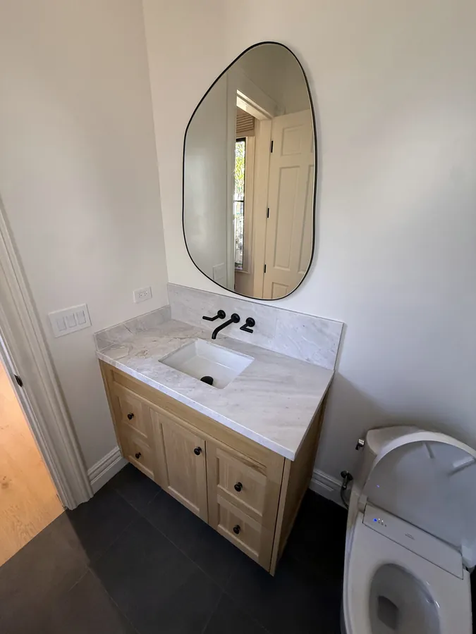 Oak shaker vanity with a stone top and an organic-shaped mirror in a powder room, Thousand Oaks
