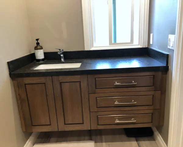 Stained wood vanity with drawers and a dark stone top, Thousand Oaks
