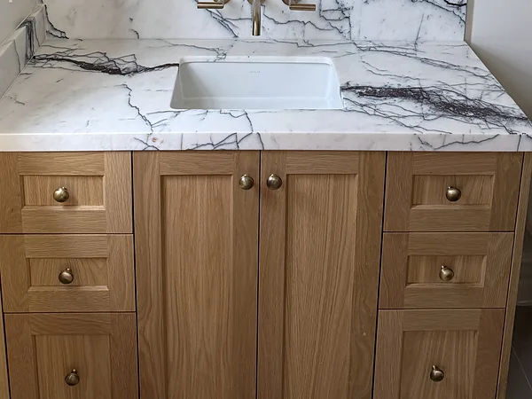 White oak shaker vanity with brass knobs under a veined stone top, Thousand Oaks