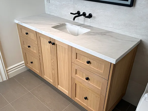 White oak shaker vanity with drawers, black knobs and a white stone top, Thousand Oaks