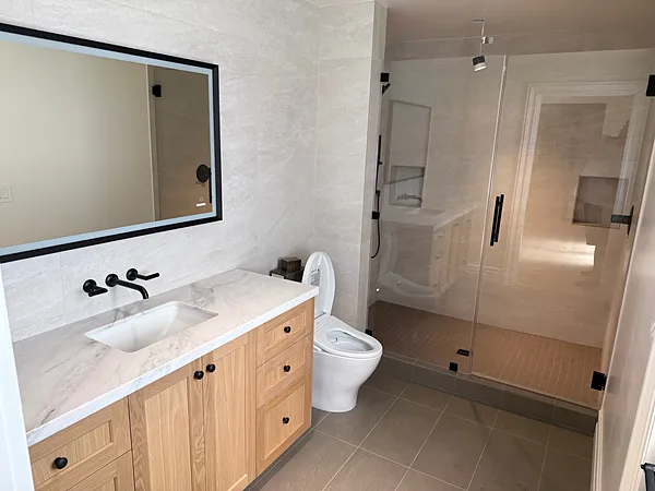 White oak vanity with a black-framed mirror next to a glass shower, Thousand Oaks