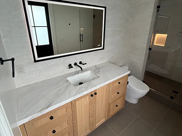 White oak shaker vanity with a marble top below a lit mirror in Lake Sherwood, Westlake Village
