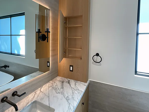 Marble-topped vanity beside a white oak tower with an open niche in Lake Sherwood, Westlake Village