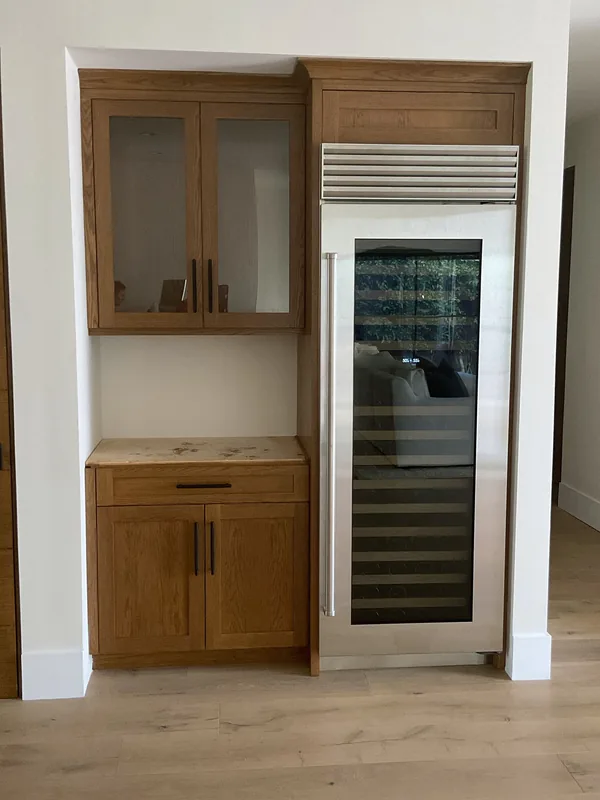 Stained wood cabinets with glass-front uppers beside a full-height wine fridge, Lake Sherwood