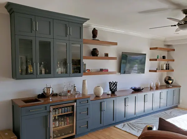 Blue-gray bar wall with glass-front uppers, a wine fridge and floating shelves